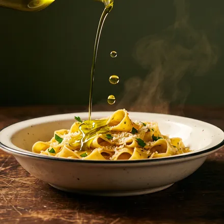 Olive oil poured over a bowl of fresh pappardelle